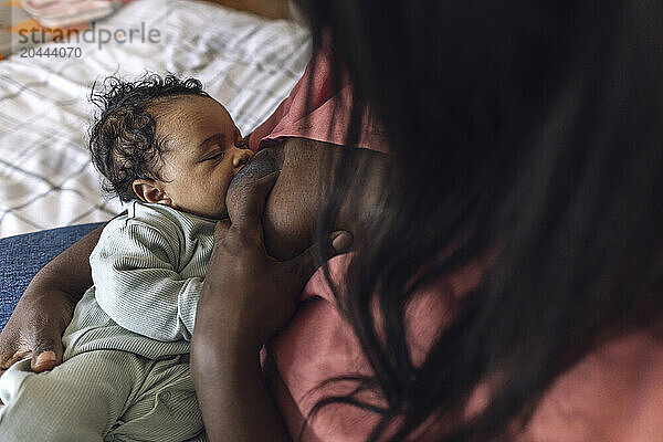 Mother breastfeeding daughter at home