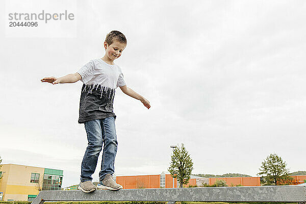 Boy with arms outstretched walking on iron railing