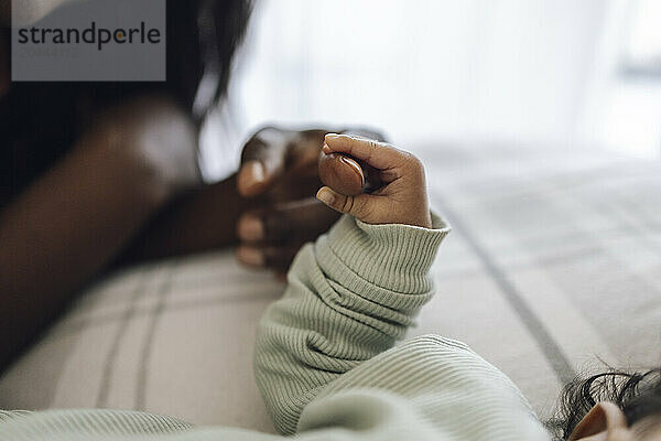 Daughter holding mother's finger at home