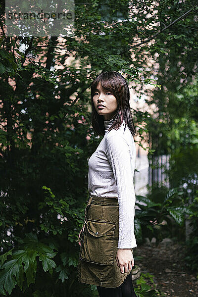 Young woman standing in front of trees in park