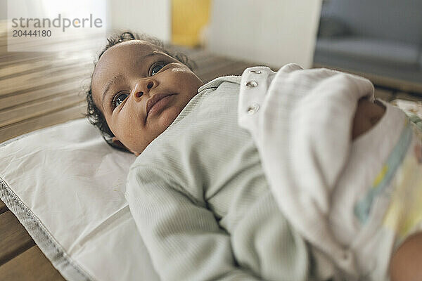 Cute baby girl lying down on table at home