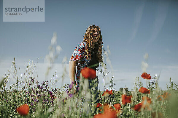 Happy woman amidst poppy flowers in meadow