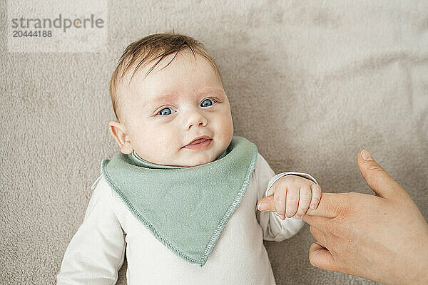 Cute baby boy holding mother's finger