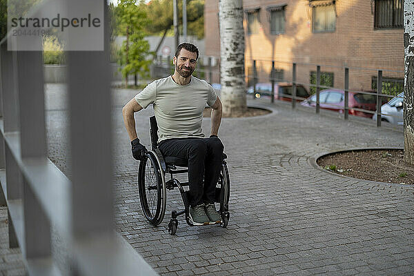 Happy man with disability sitting on wheelchair at street