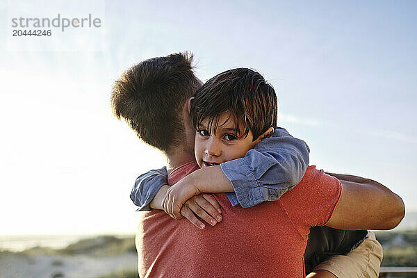 Smiling boy embracing father at beach