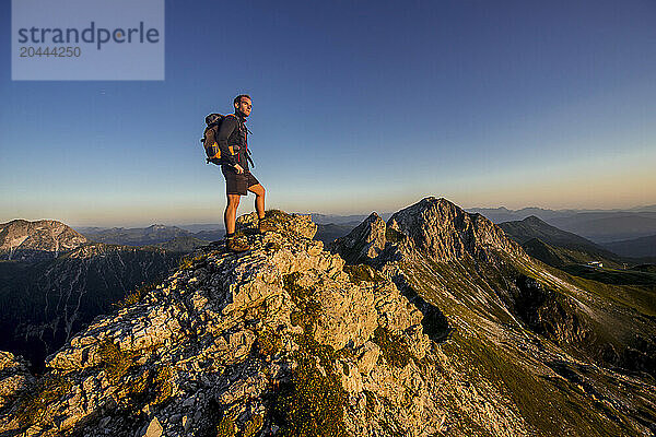 Man standing on Steinfeldspitze rock at sunrise in Altenmarkt  Zauchensee  Salzburg  Austria