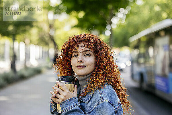 Smiling redhead young woman with reusable coffee cup