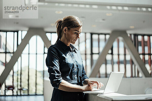 Businesswoman working on laptop at airport lobby