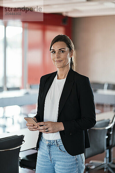 Smiling businesswoman using smart phone at office