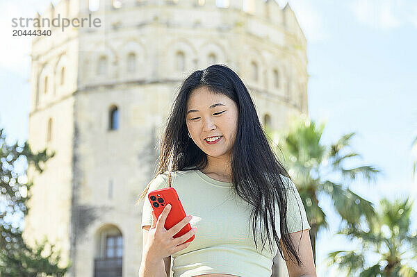 Beautiful woman using smartphone in front of Torre del Oro