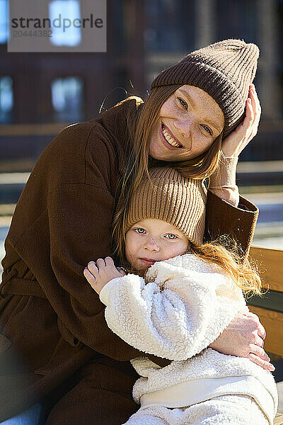 Happy mother and daughter embracing each other on sunny day