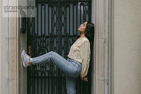 Woman with eyes closed leaning on wall in doorway