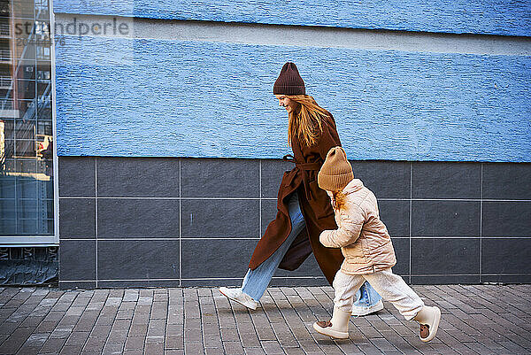 Mother and daughter walking together on footpath