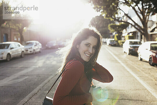 Happy woman crossing road at sunny day