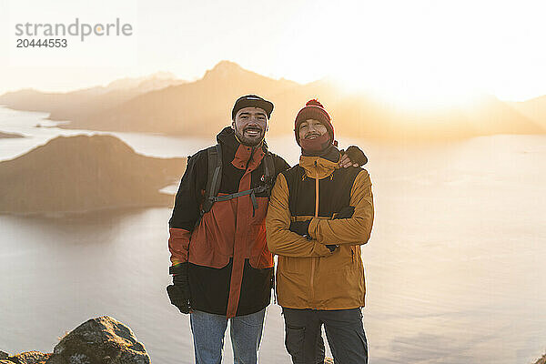 Happy friends standing in front of Norwegian sea at sunset  Norway