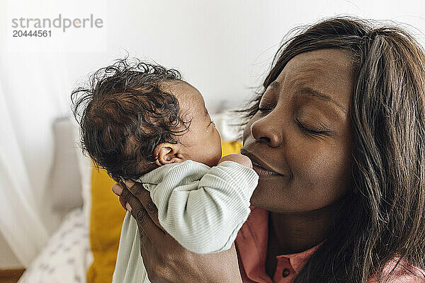 Mother with eyes closed taking care of daughter at home