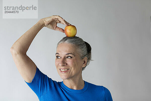 Smiling senior woman with apple on head