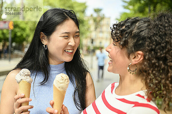 Happy friends eating ice cream and enjoying at street