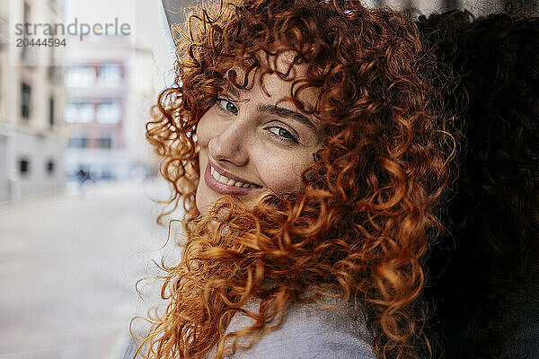 Smiling beautiful young redhead woman with curly hair