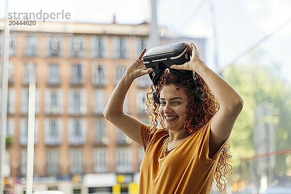 Happy young redhead woman wearing virtual reality simulator