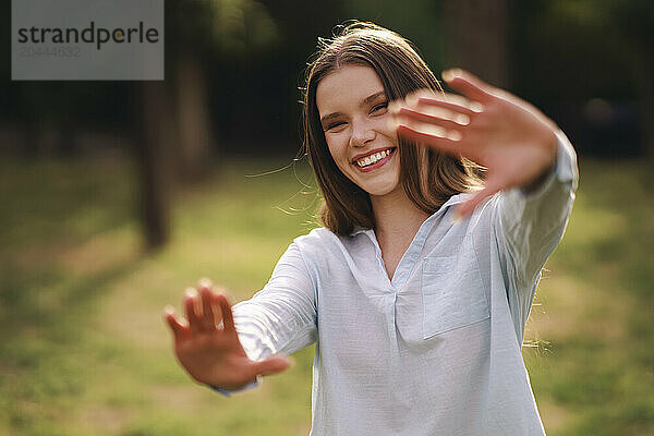 Playful woman standing gesturing at field