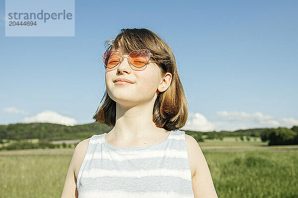 Young girl with heart shaped glasses standing at field