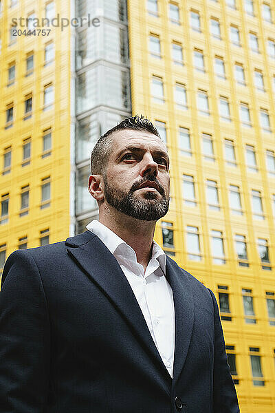 Businessman standing in front of yellow colored building