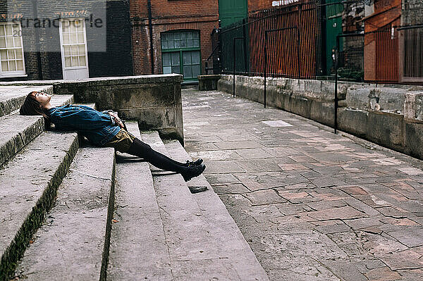 Young woman lying on steps near buildings