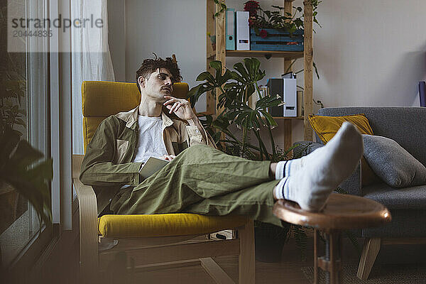 Man resting on armchair in living room at home