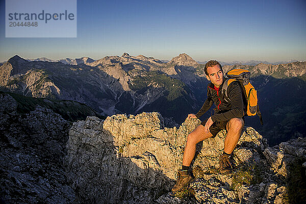 Man sitting on Steinfeldspitze rock under sky at sunrise in Altenmarkt  Zauchensee  Salzburg  Austria