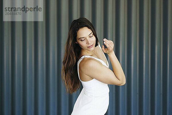 Beautiful young woman dancing in front of wall