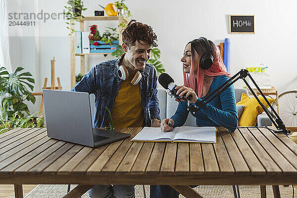 Happy influncers recording podcast with microphone at home