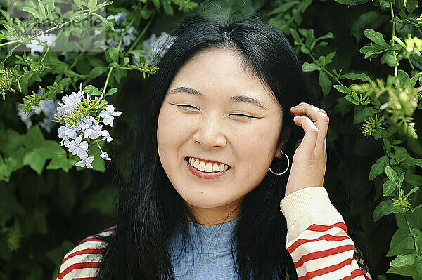 Happy woman with eyes closed standing near flowers at park