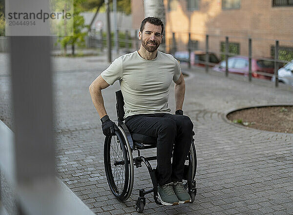 Smiling man with disability sitting on wheelchair at street