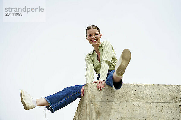 Playful woman sitting and enjoying on wall