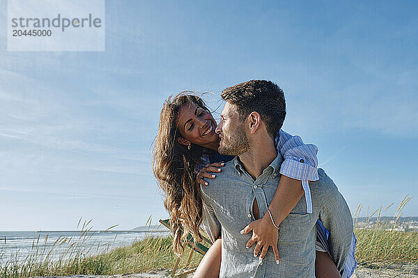 Man piggybacking girlfriend at beach