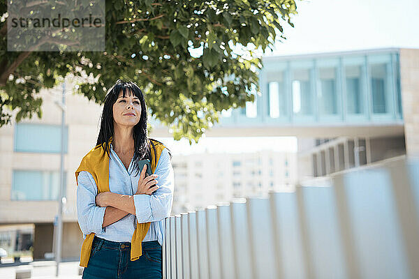 Businesswoman standing with arms crossed near railing