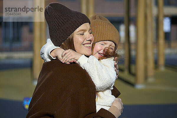 Mother hugging daughter on sunny day