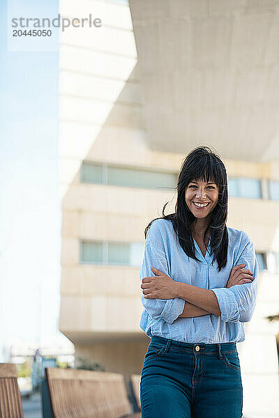 Happy businesswoman standing with arms crossed