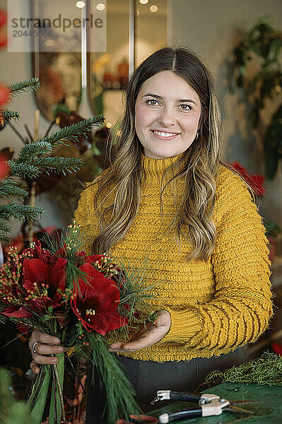 Smiling young florist holding flower bouquet