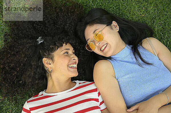 Happy friends lying on grass at park