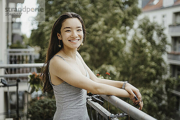 Portrait of happy young woman standing in balcony