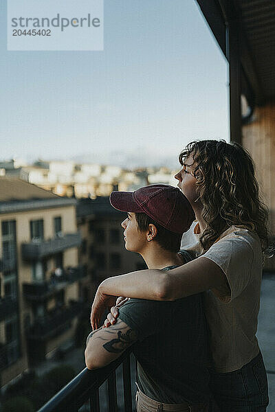 Lesbian couple looking at view while standing in balcony at home