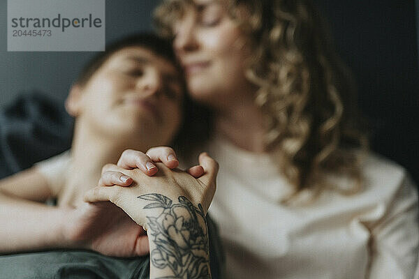 Lesbian woman with tattooed arm holding girlfriend's hand