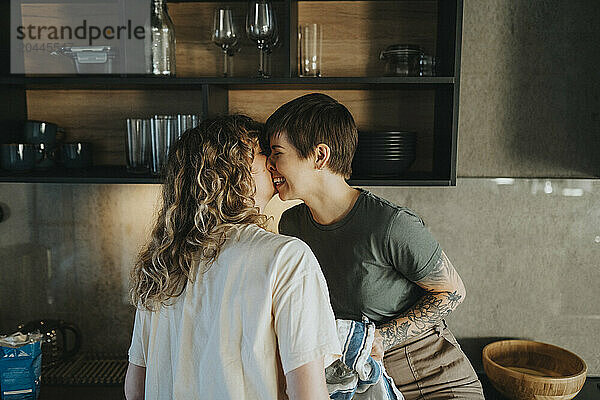 Happy lesbian couple having fun while doing kitchen chores at home