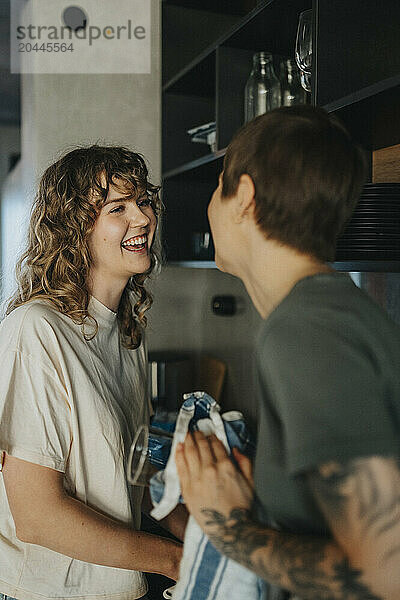 Happy lesbian woman doing kitchen chores with girlfriend at home