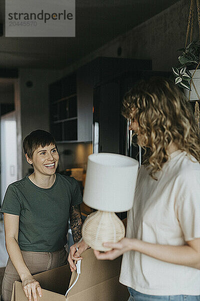 Smiling lesbian couples packing stuff in cardboard box during relocation