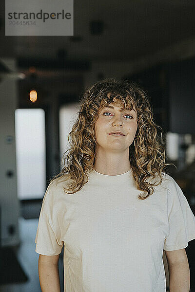 Portrait of woman with curly hair standing at home