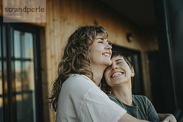 Happy lesbian couple standing together in balcony at home