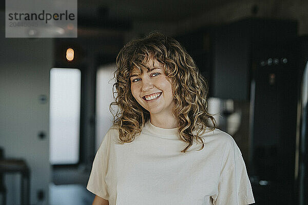 Portrait of happy beautiful woman with curly hair at home